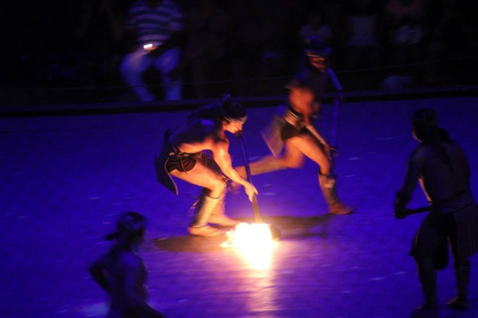 Ancient Mayans playing a game resembling field hockey with a ball of fire.